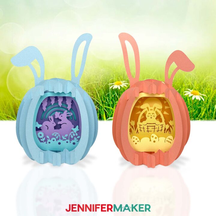Two paper pop-up Easter eggs, one in shades of blue with a bunny and flower scene inside, and one in shades of yellow and pink with a bunny in a basket scene inside.