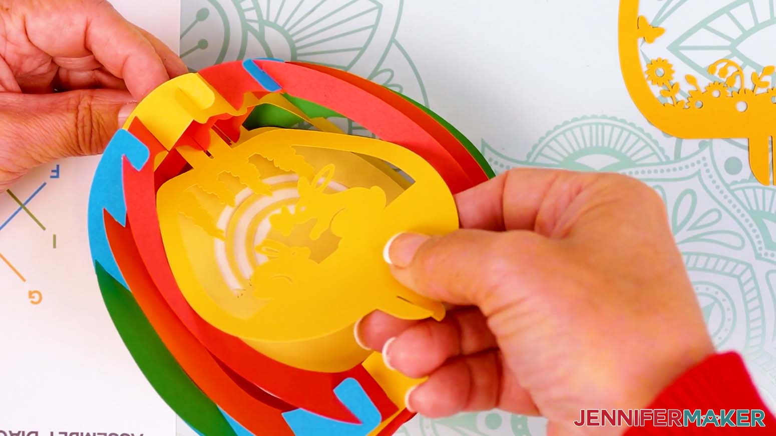 Insert the middle scene layer's top tab into the bump at the top inside of the assembled paper pop up Easter egg.