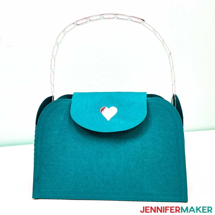 Teal blue embossed paper purse with a silver foil handle and heart