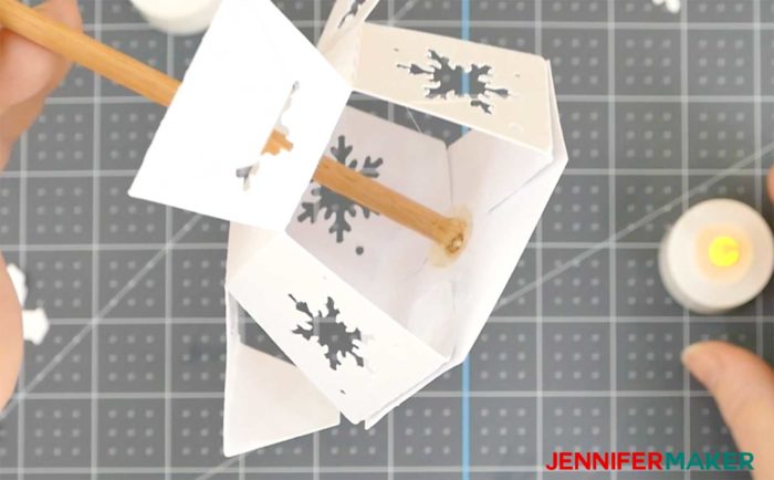 Hot glue holds the dowel inside the base of the paper snowflake Christmas tree
