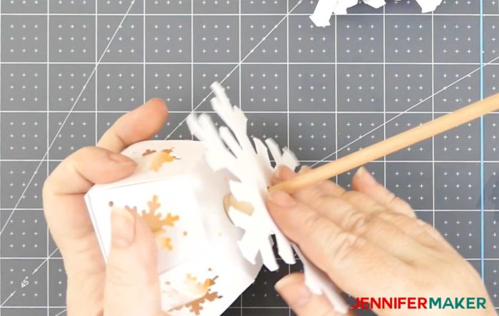 Slide the largest paper snowflake onto the dowel to make the paper snowflake tree