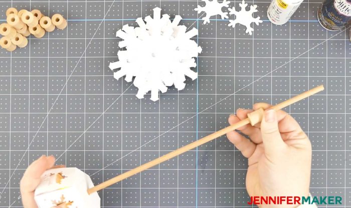 Sliding a wood spool over a wood dowel to make a paper snowflake christmas tree luminary