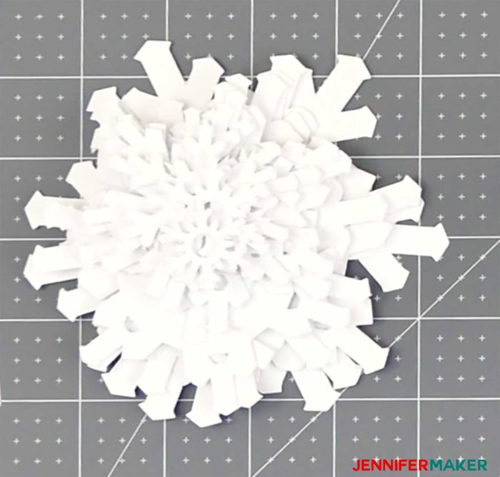 Paper snowflakes arranged in a pile from largest to smallest to make the paper snowflake Christmas tree luminary