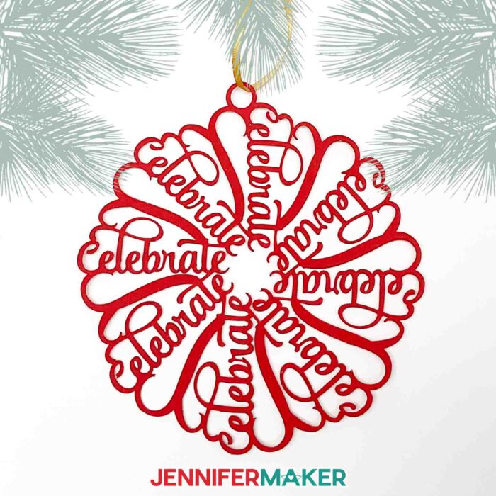 A red snowflake ornament with the word "Celebrate" hangs from a tree. Make a personalized snowflake ornament with Jennifer's tutorial.