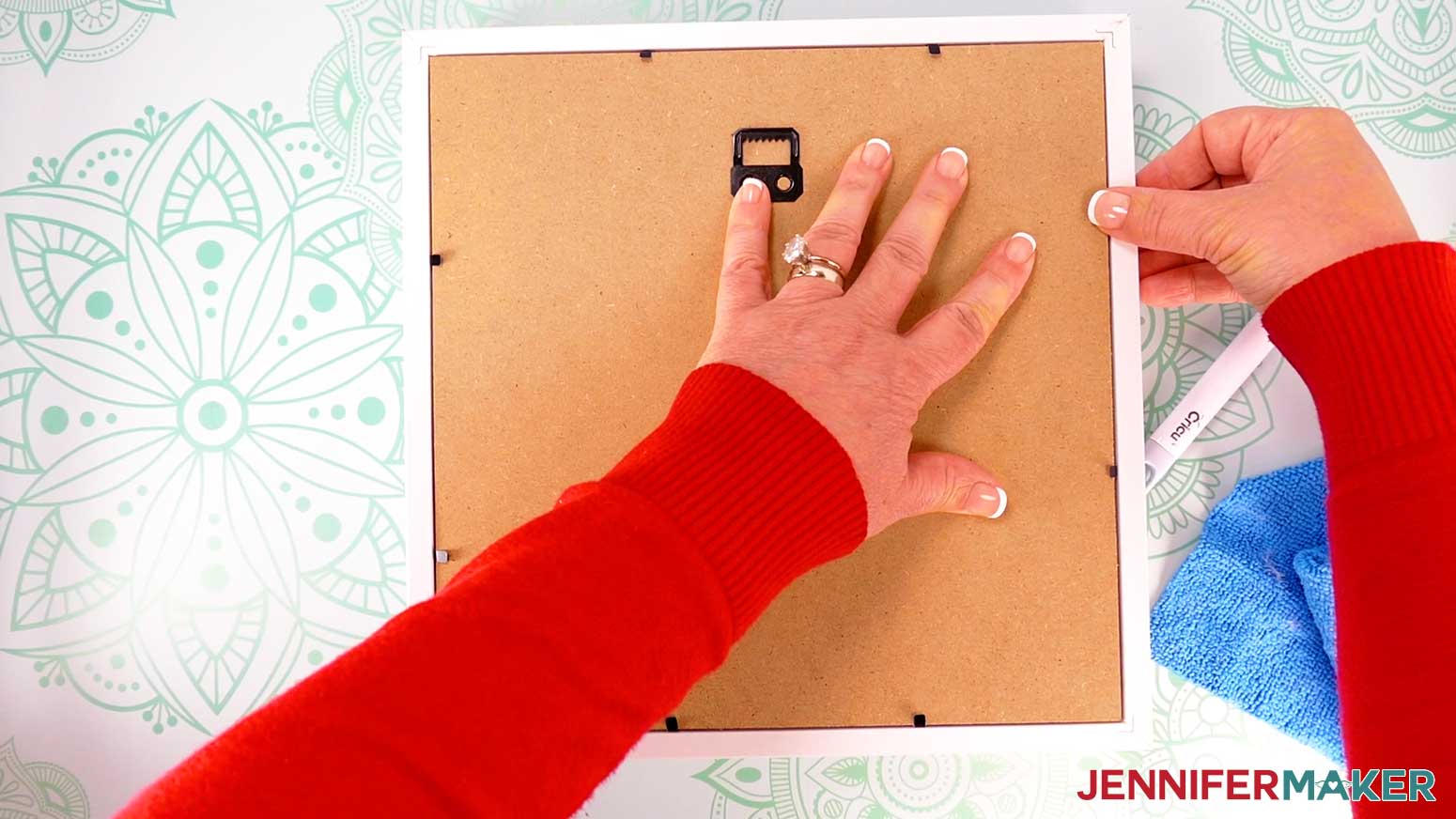Place the backing board on top of the spacer, with the hanger positioned at the top, and press down the metal tabs to secure it.