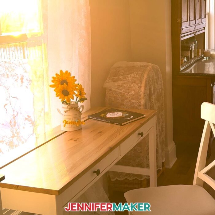 A vase of Easy Pipe Cleaner Flowers sits in a hazy, sun-filled room at golden hour. The flowers are crafted with yellow pipe cleaners to look like realistic sunflowers