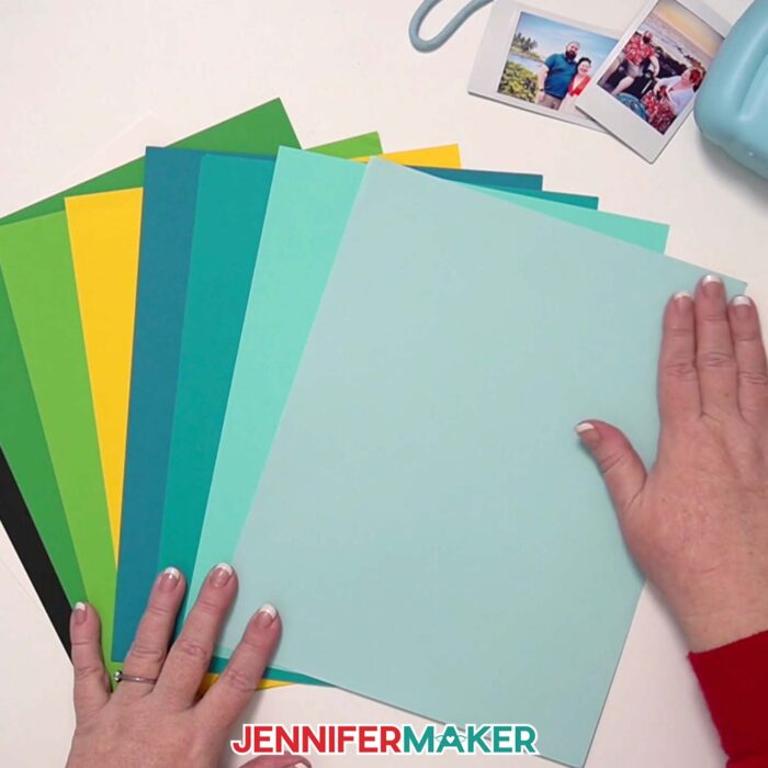 Hands fan out a variety of colored cardstock used to make Polaroid Shadow Box projects