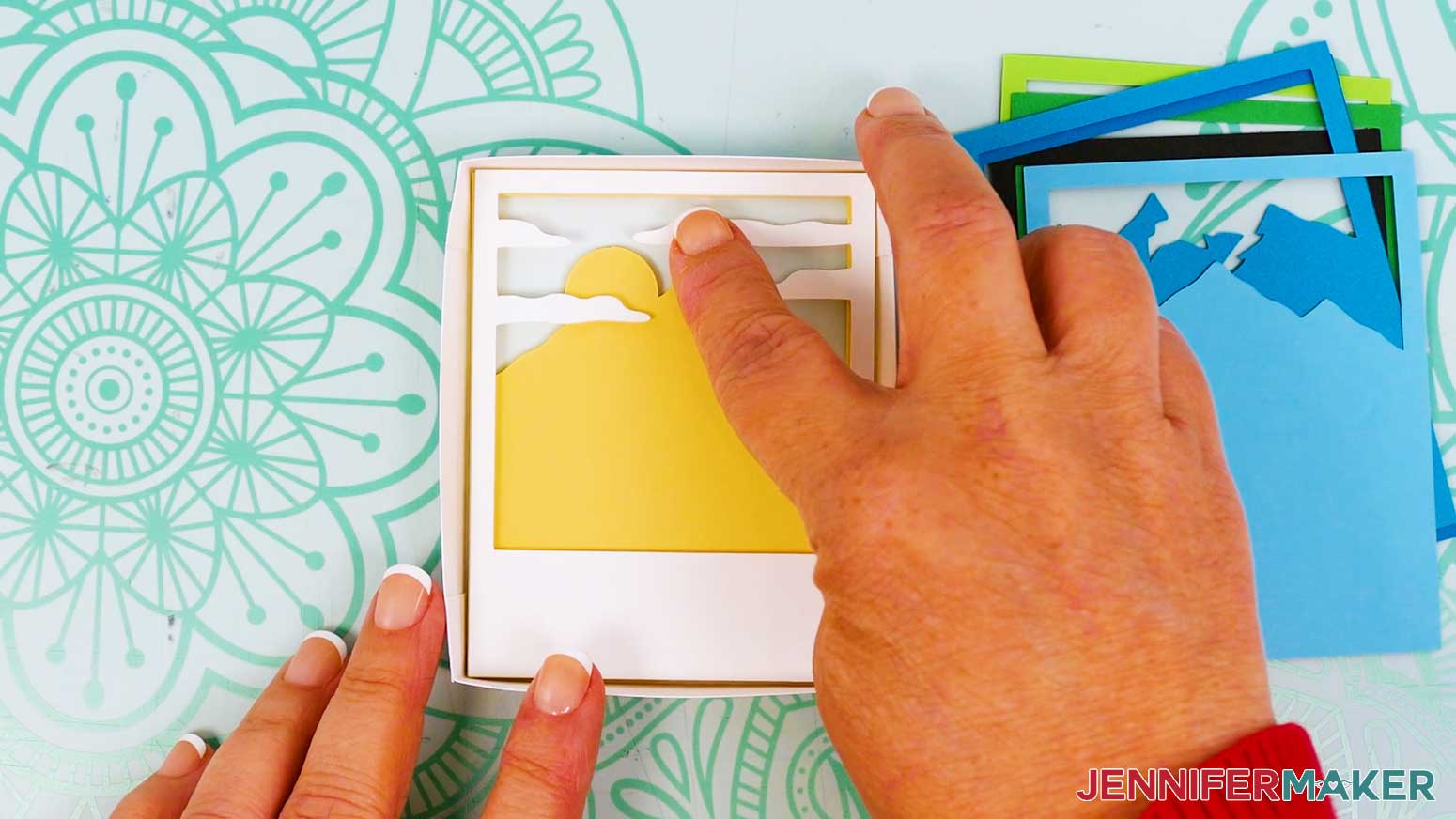 Press the mountain scene's white layer into place on top of the light blue and yellow layers inside the Polaroid Shadow Box frame.