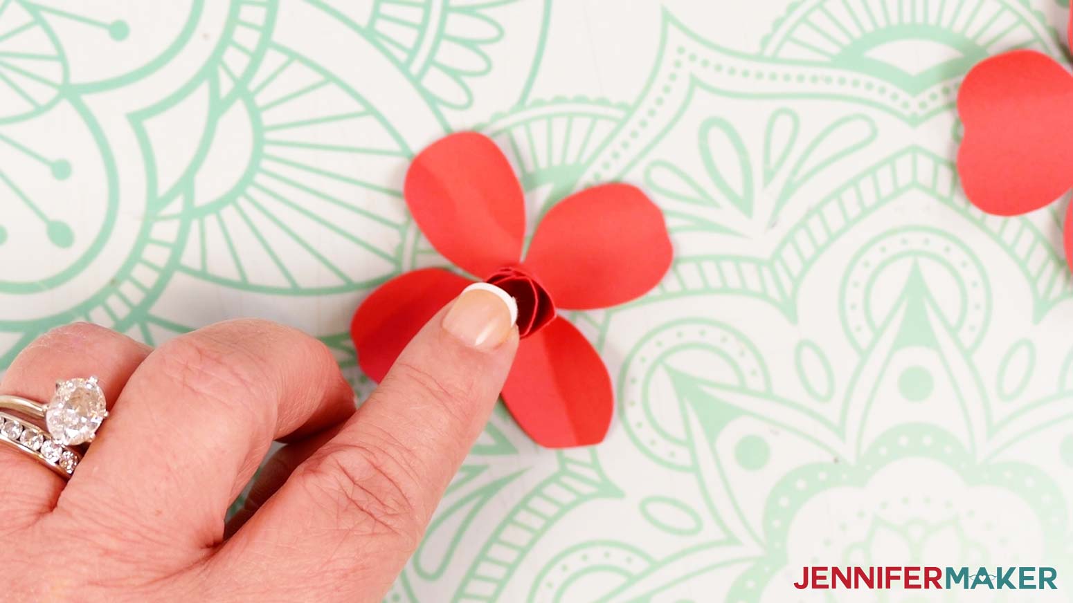 Add a dot of glue to the bottom of the rose bud, then place it onto the center of the middle rose piece.