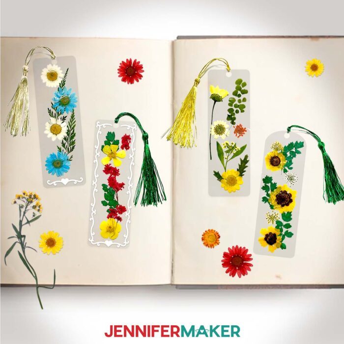 Four rectangular pressed flower bookmarks with colorful flowers between laminated layers inside an open sketchbook.