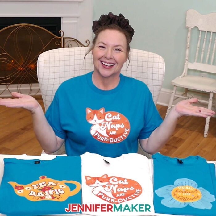 Jennifer Maker shows off a collection of turquoise and white Print Then Cut Iron-On T-shirts on display, featuring cute and cozy designs of cats, teapots, and blooms with quotes