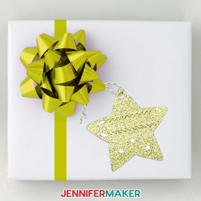 Learn how to make pull tab gift tags with JenniferMaker's tutorial! A star pull tab gift tag hangs from a bow on a wrapped gift.