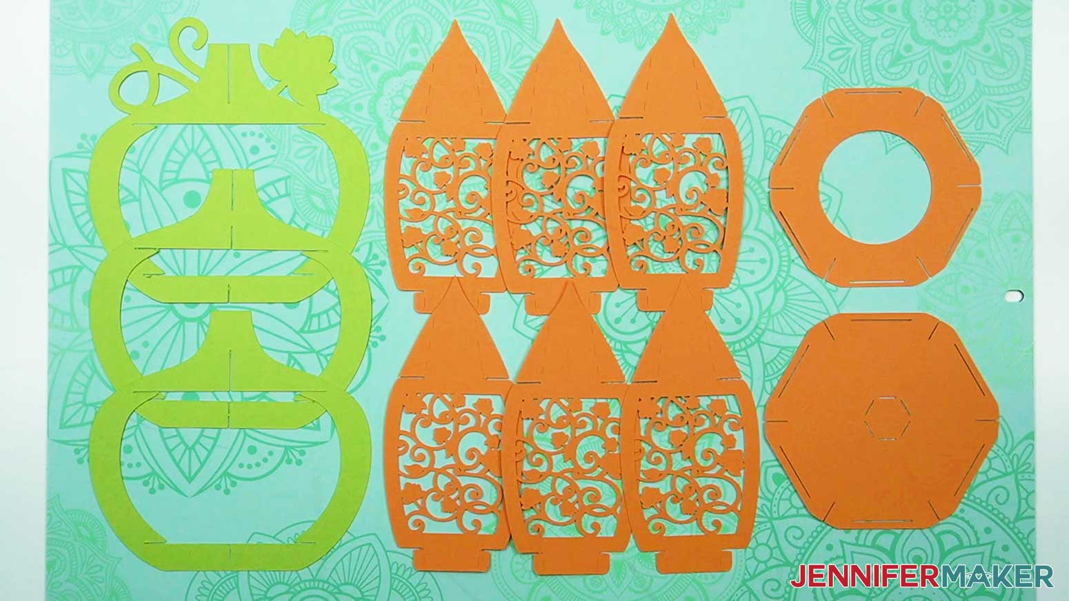 Cut cardstock pieces for the 3D pumpkin lantern, showing three green frame pieces, six orange decorative panels, and two orange hexagonal base pieces