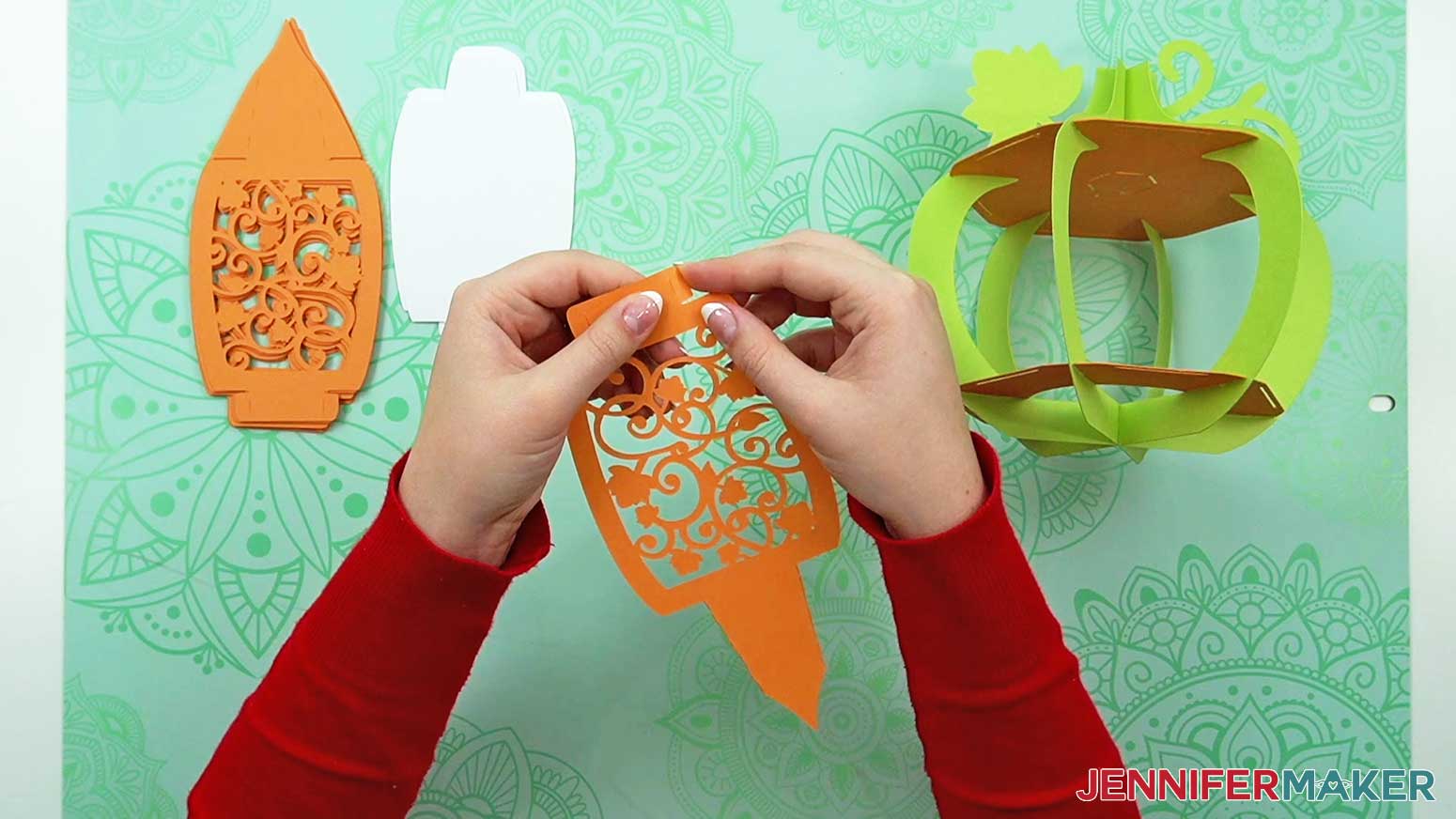 Fold the four tabs at the top and bottom of the 3D pumpkin lantern's decorative panel inward along the dashed cut lines