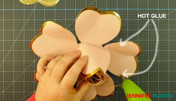 Gluing the paper petals onto a giant rose gold paper flower