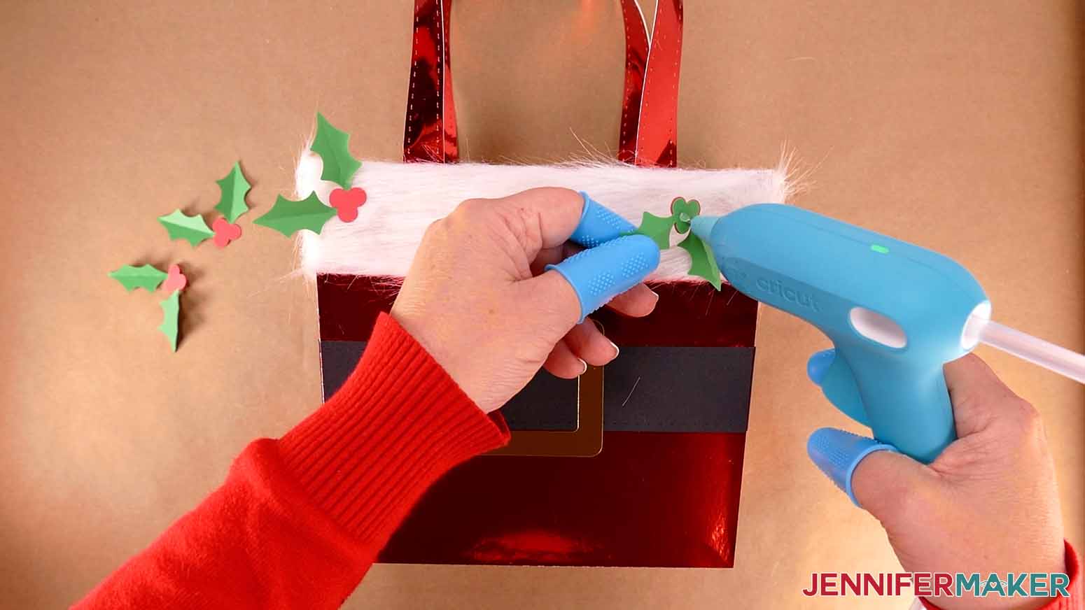 Add a small dot of hot glue to the back of a holly piece and attach it to the Santa purse.