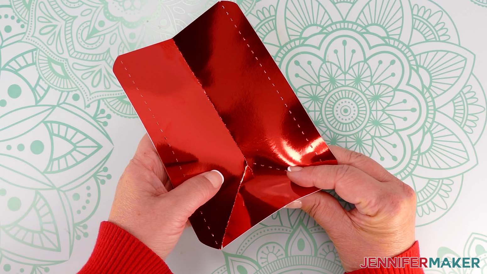 Fold along the left and right diagonal crease lines, toward the pretty side, from the meeting point down to the bottom edge of the Santa purse side piece.
