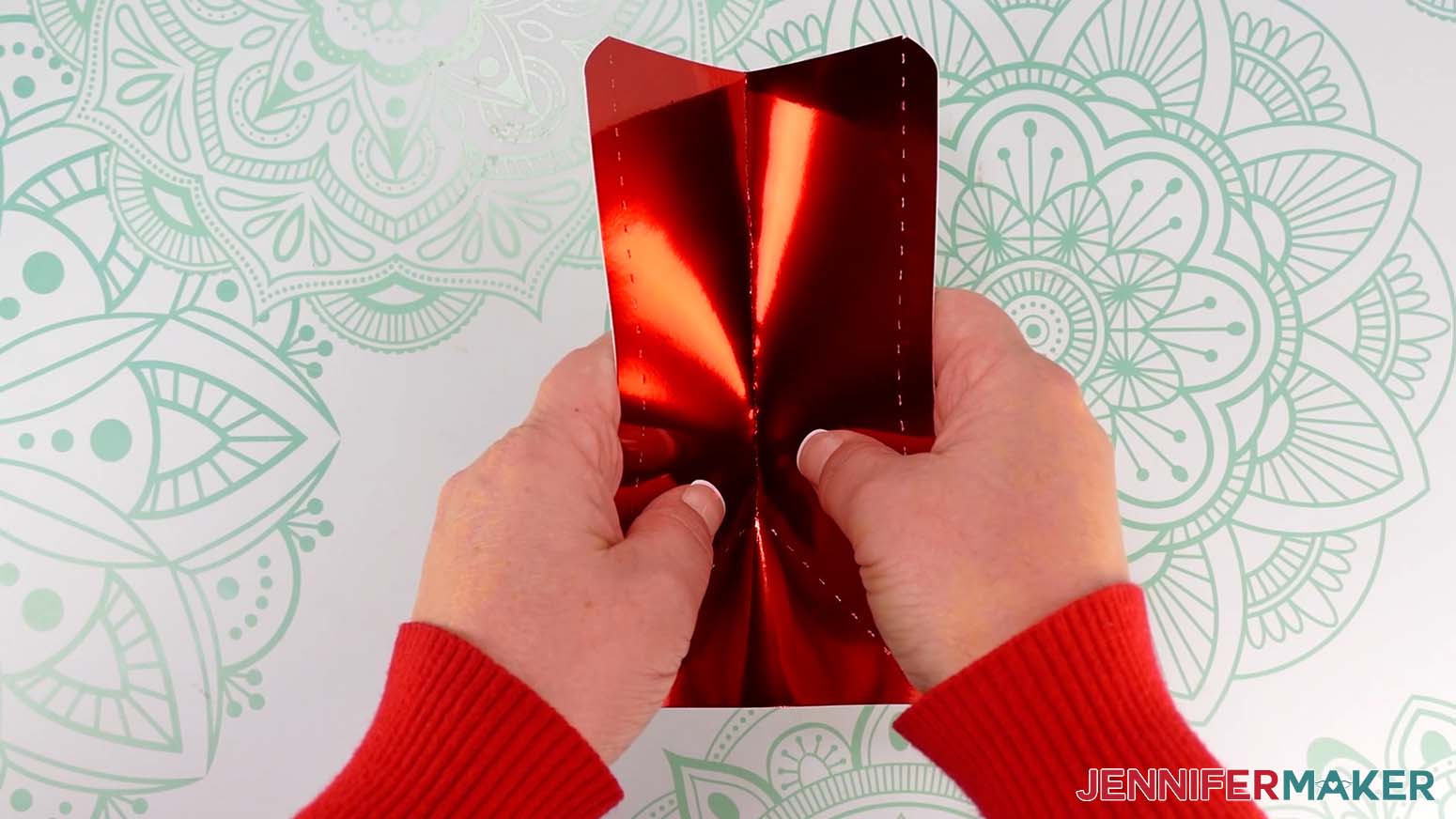 Fold down from the top along the center crease line, toward the pretty side, to the point where three lines meet on the Santa purse side piece.