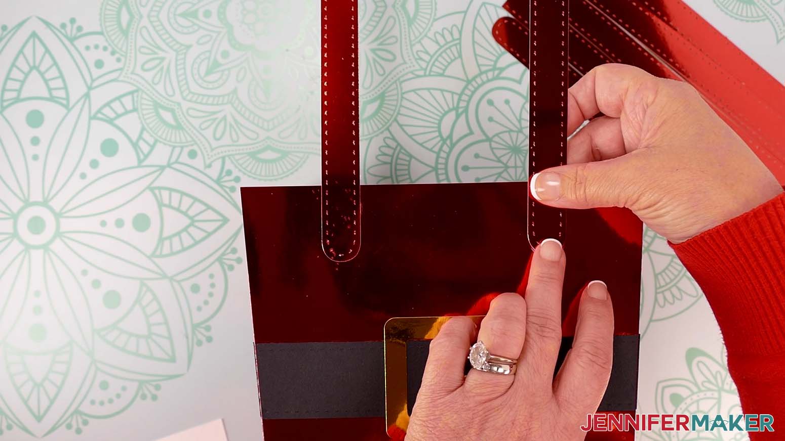 Attach the handle pieces to the Santa purse&rsquo;s top corners so they're oriented with the handles straight up and perpendicular to the top.