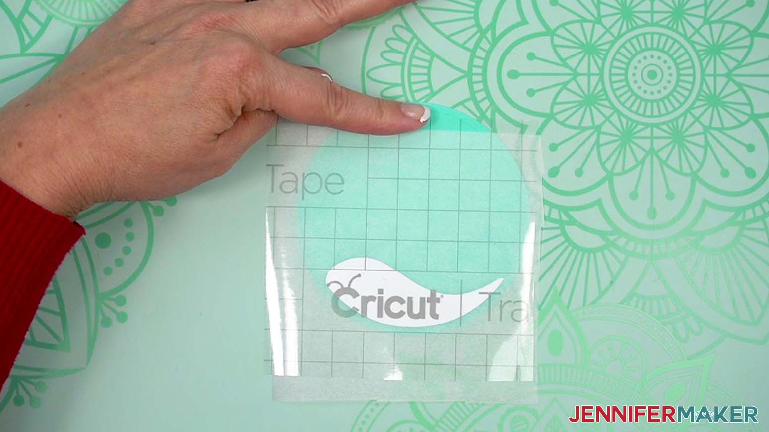 Finger holding transfer tape near top of ornament