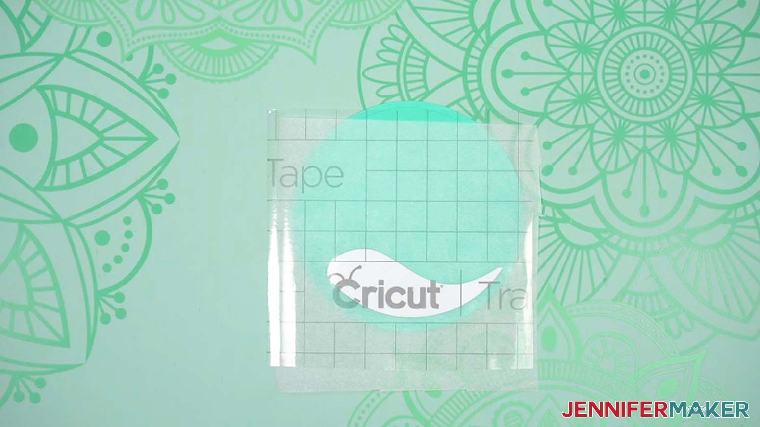 Vinyl on the transfer tape is lined up on cardstock with parchment paper