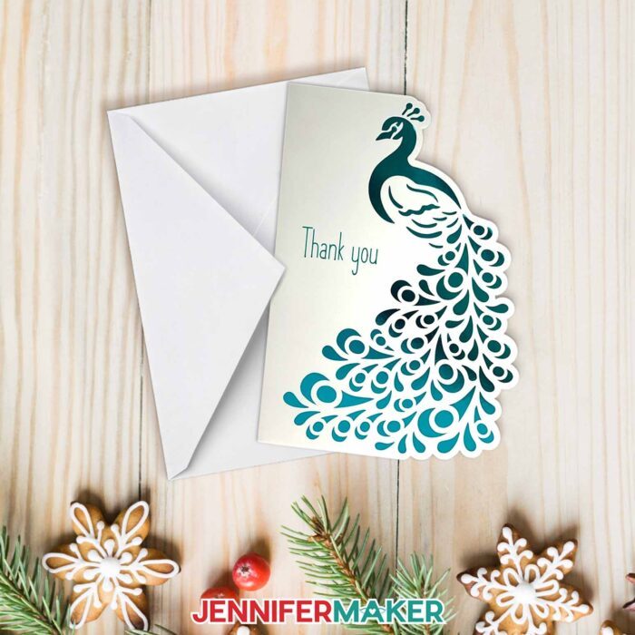 Learn how to design side edge cards with Jennifer Maker's tutorial! A beautiful card with a peacock and decorative edges sit on a holiday table.