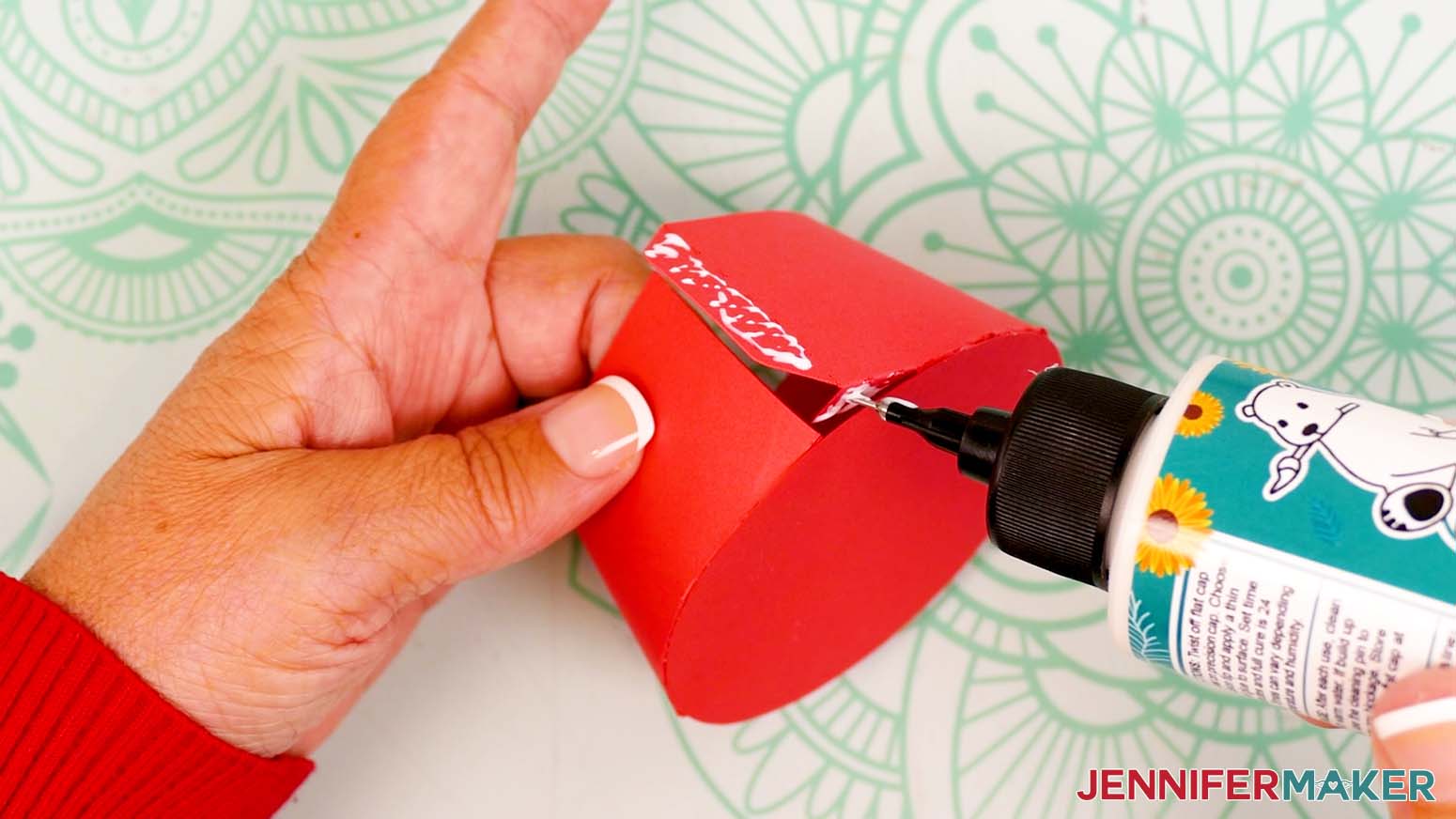 Add craft glue to the bottom of the gift box base's last small tab and the outside of its side tab.