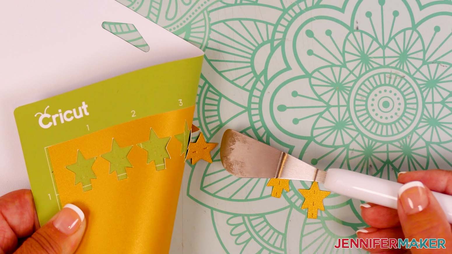 A Cricut spatula being used to remove cut star pieces from a machine mat.