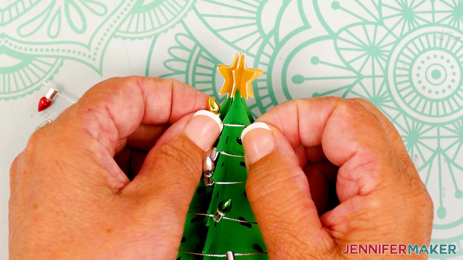 Press the last light into place at the top of the snow globe gift box's tree.