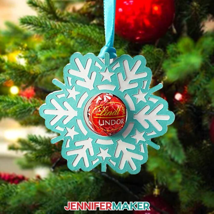 Learn how to make snowflake candy holder with JenniferMaker's new tutorial! A snowflake candy holder ornament hangs on a Christmas tree with white lights and red bulb ornaments.