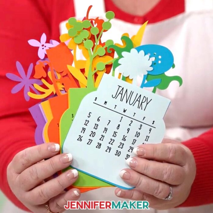 Jennifer Maker fans out the layers for the multicolor floral Stacked Calendar she made