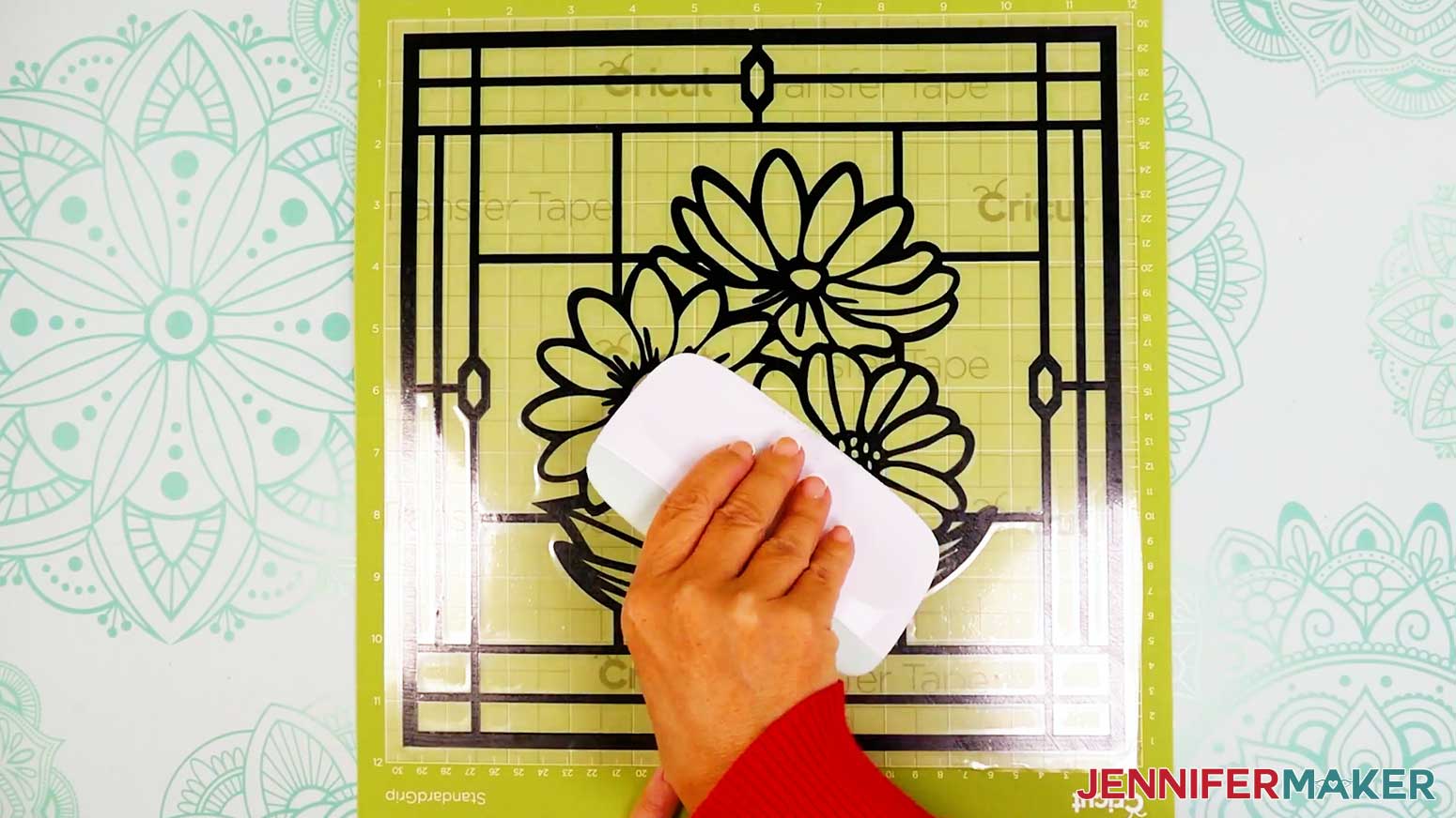 Use the scraper to burnish the vinyl into place on the acetate layer of the stained glass design before removing the transfer tape.