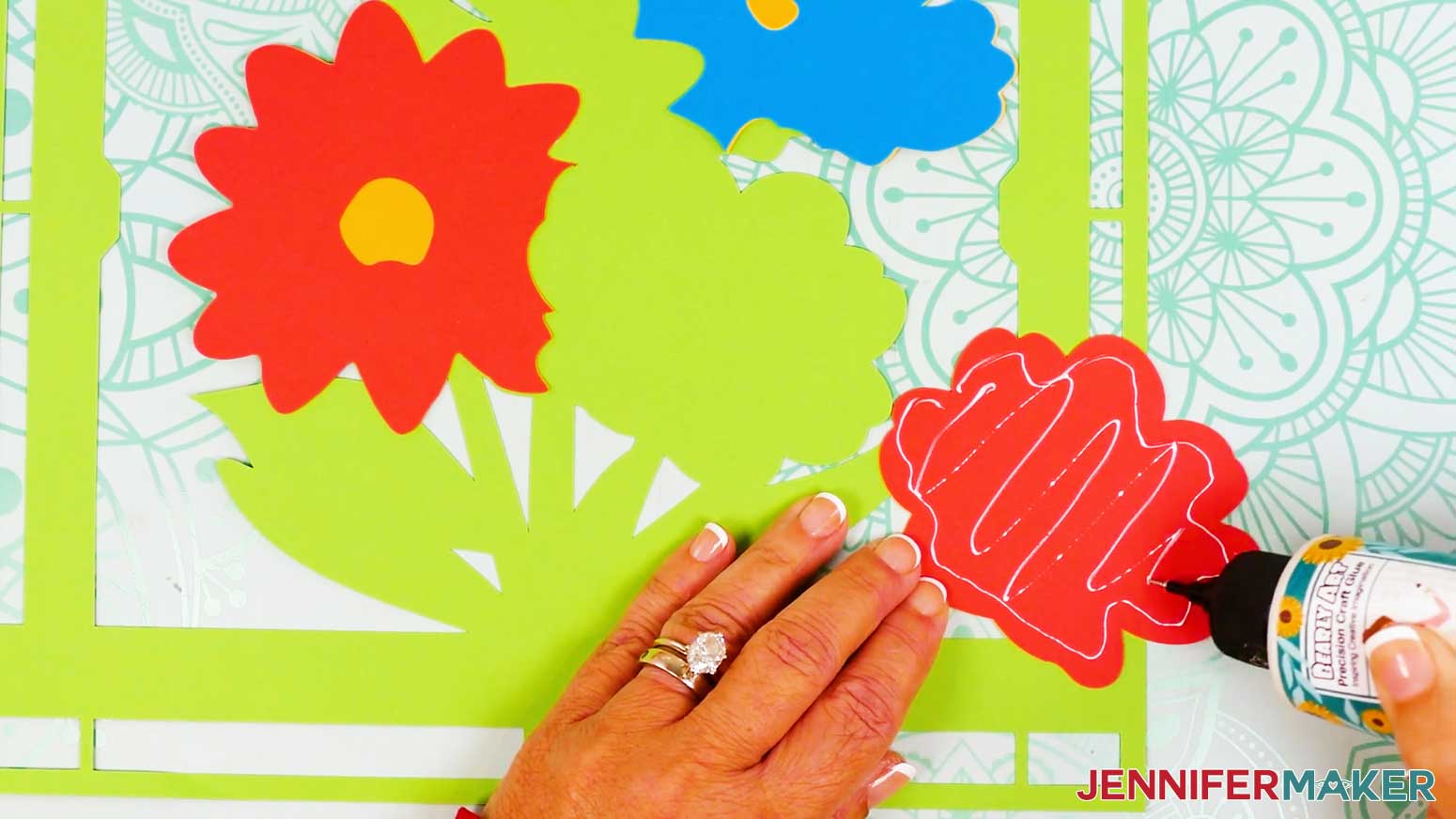 Place a small amount of glue on the back of the flower piece to adhere it to the back cardstock layer of the stained glass design.