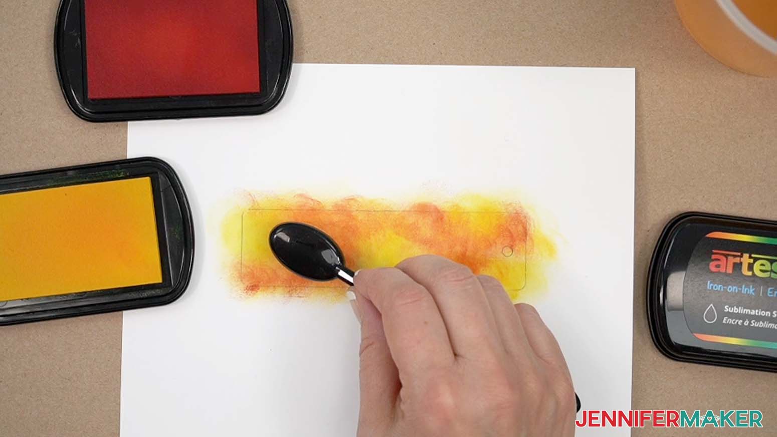 Applying orange ink to the paper with a blending brush, yellow ink already applied.