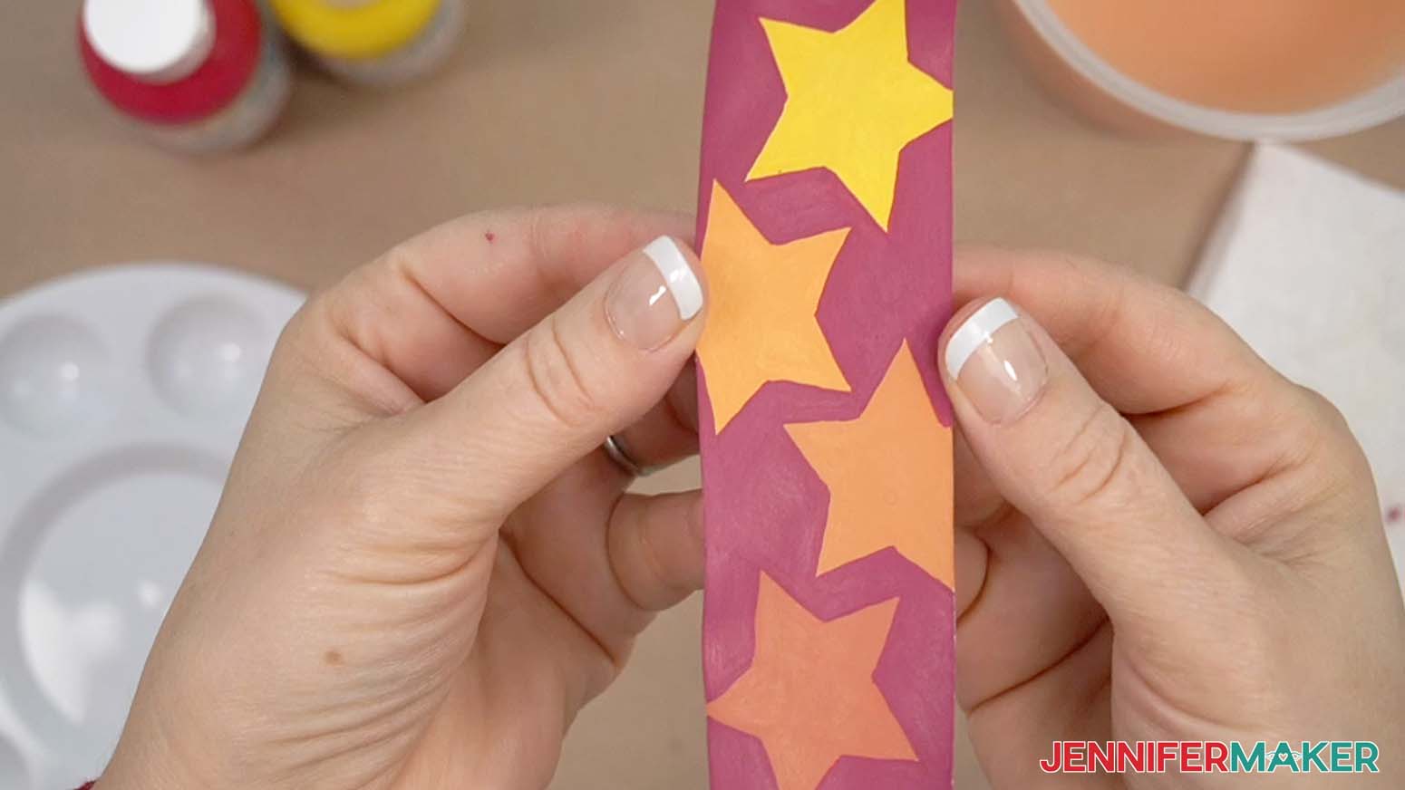 Bookmark painted with sublimation paint the stars are yellow and orange with a red background.