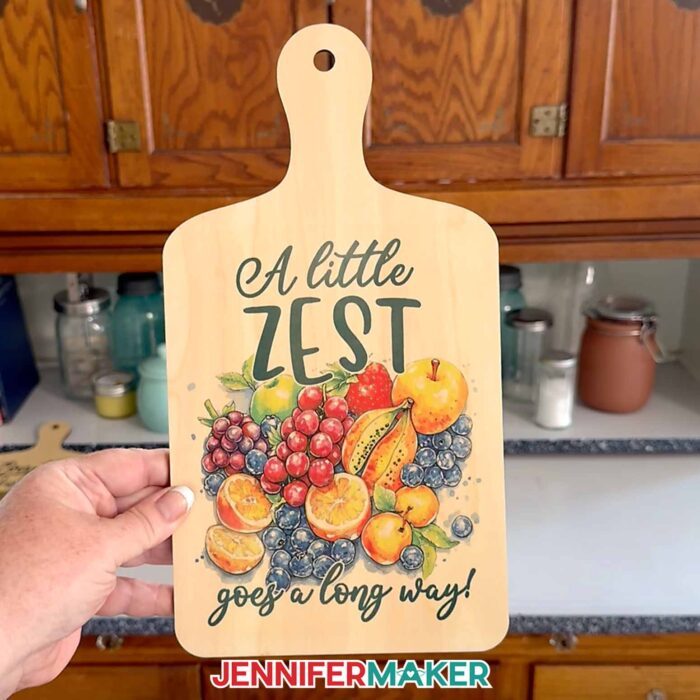A sublimated charcuterie board with a fruits design and the words "A little zest goes a long way!"