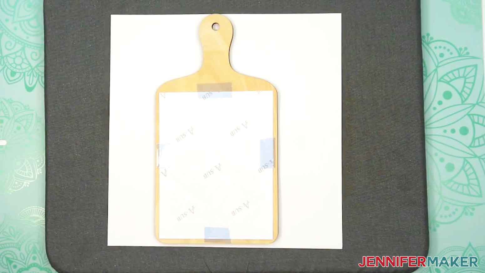 Place the prepared charcuterie board and printed sublimation design onto a pressing pad and blank cardstock.
