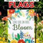 Make DIY sublimation garden flags with JenniferMaker's tutorial! A brightly colored floral garden flag hangs in a garden full of spring flowers. The flag reads "Live Life in Full Bloom".