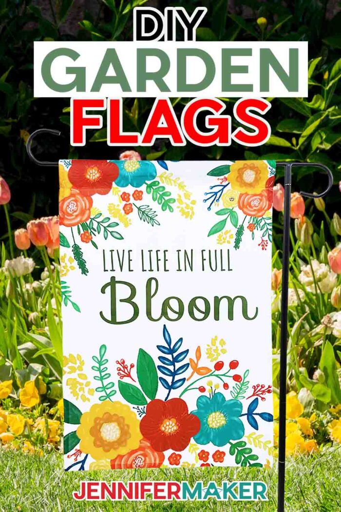 Make DIY sublimation garden flags with JenniferMaker's tutorial! A brightly colored floral garden flag hangs in a garden full of spring flowers. The flag reads "Live Life in Full Bloom". 