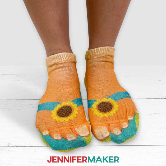 Person wearing sublimation socks showing feet wearing flip flops with sunflowers at the toe strap.