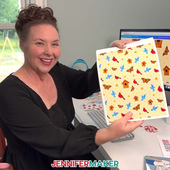 Jennifer Maker shows of a a sheet of patterned paper with birds and butterflies that she made as part of the Seamless Pattern In Canva tutorial