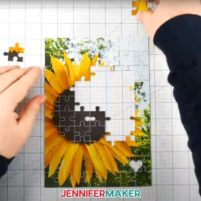 Make a puzzle on your Cricut with JenniferMaker's new tutorial! Jennifer's hands putting together a puzzle of a sunflower.