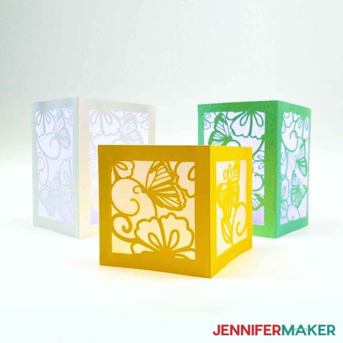 Yellow, green, and white tea light holders on white background