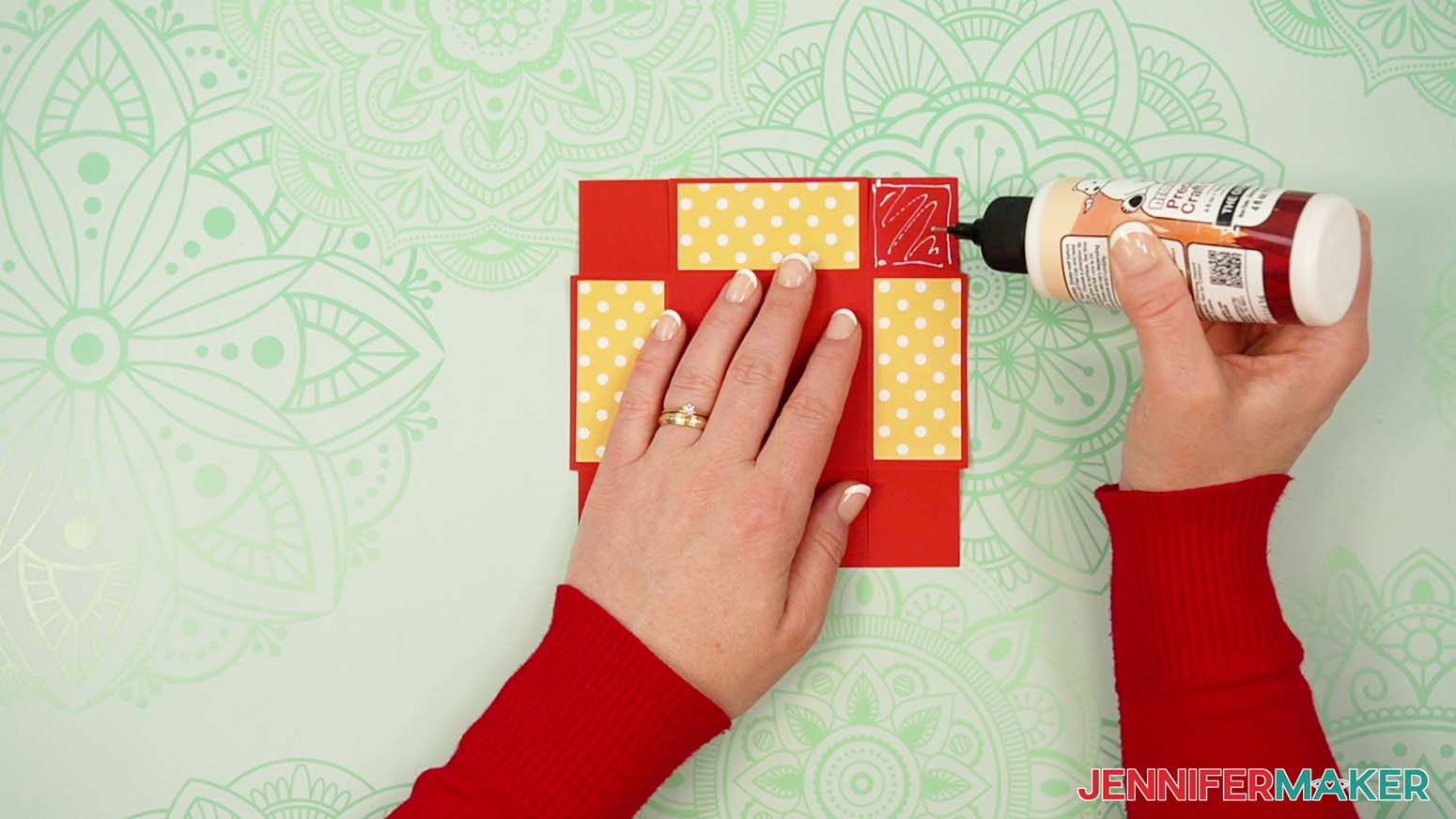 Add glue to the corner tab of the tower gift box lid.