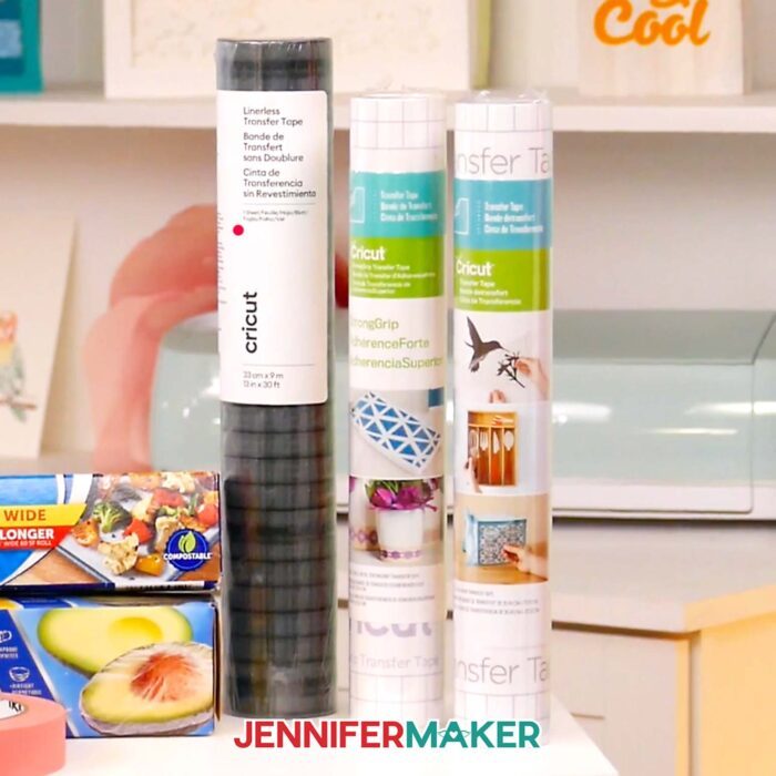 Three rolls of transfer tape, including Cricut linerless transfer tape, Cricut StrongGrip transfer tape, and Cricut StandardGrip transfer tape, lined up in Jennifer's craft room. Learn how to use transfer tape with vinyl projects with JenniferMaker's new tutorial!