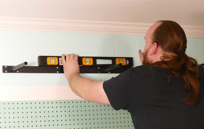 Checking that the floating shelf bracket is level as we install under shelf lighting cheap and easy