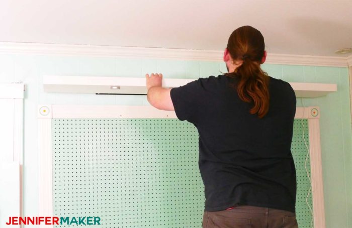 Sliding the floating shelf with lights onto the bracket hardware to install under shelf lighting cheap and easy