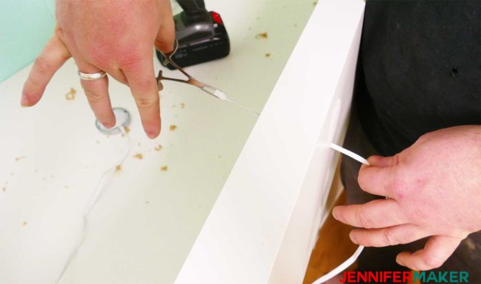 Threading the cord through the hole in the shelf to install under shelf lighting cheap and easy