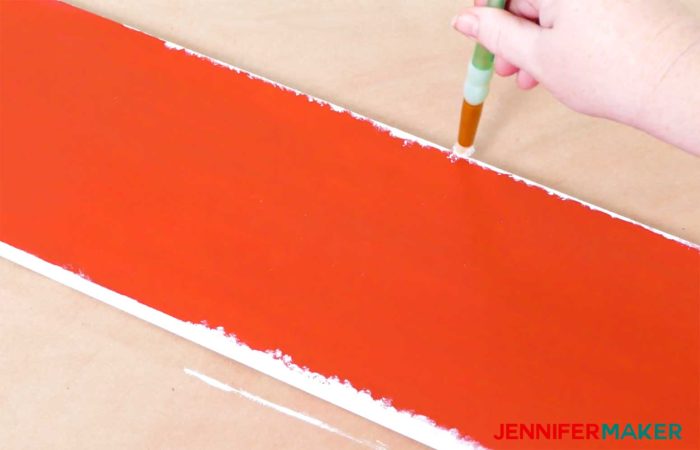 Creating a snowy look with white paint on a red board to create a vertical holiday sign