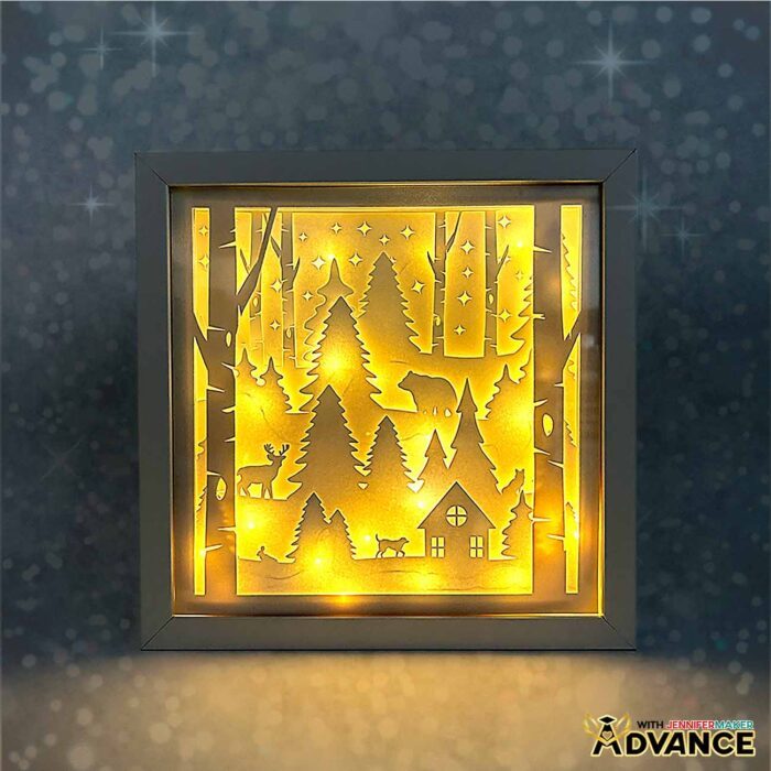 A custom forest scene inside a shadow box, made with layers of cardstock and glowing lights.